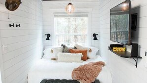 Une chambre à coucher avec un lit, une télévision et une fenêtre.