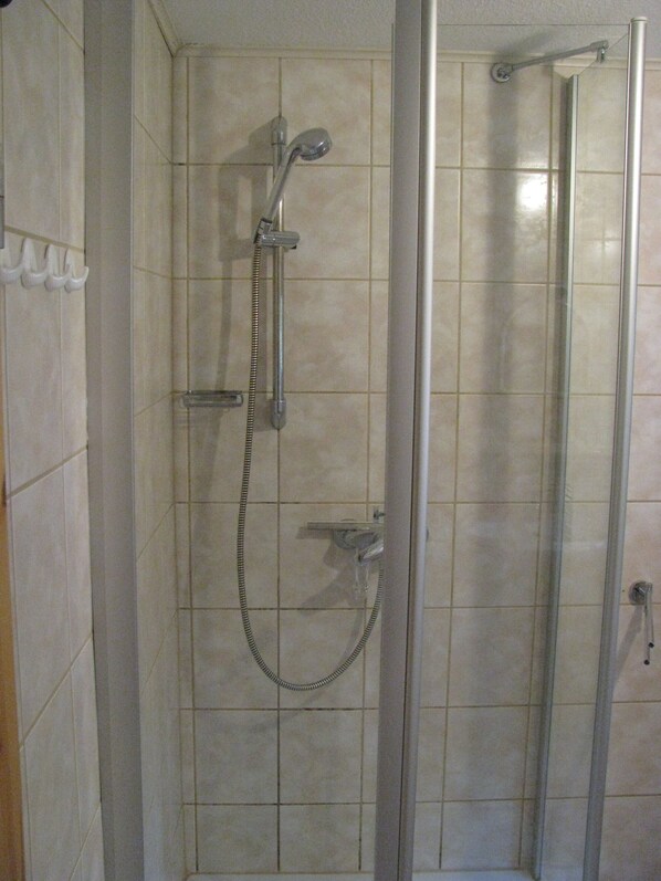 A shower with a handheld showerhead and a fixed showerhead, both mounted on a wall with a tiled floor. - Ferienhaus Direkt am Küstenwald nur 10 Minuten Fußweg zum Strand (Zinnowitz)