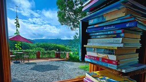 A view through a window with a bookshelf full of books and a sign reading "READING WONDERLAND". - The River House (Puerto Quito)