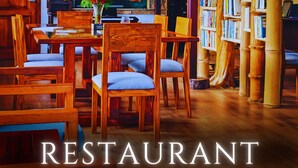 A cozy wooden interior with a large wooden wall displaying various phrases, a table with chairs, and a bookshelf filled with books. - The River House (Puerto Quito)