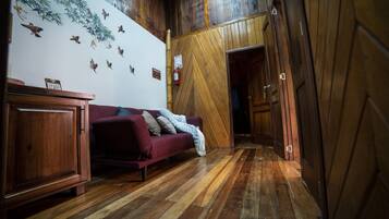 Un pasillo con suelo de madera, un sofá rojo y un armario.