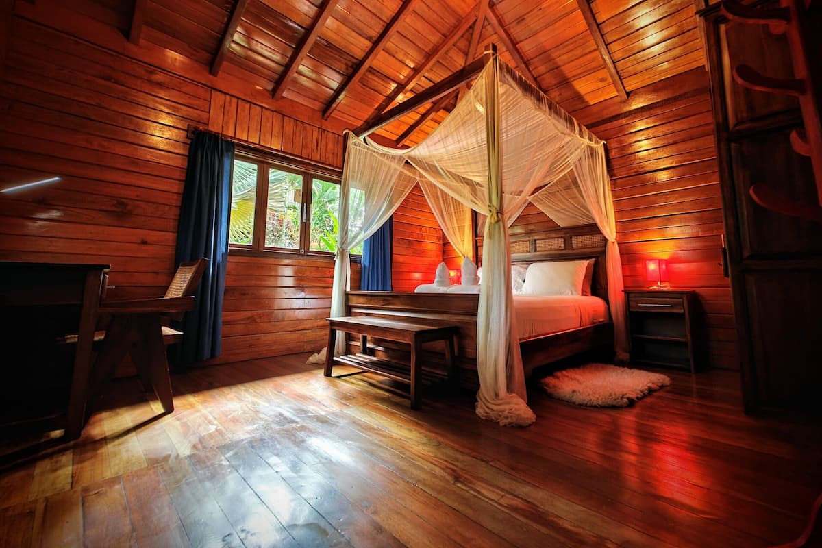 Una habitación de cabaña de madera con una cama con dosel, un escritorio y una silla.
