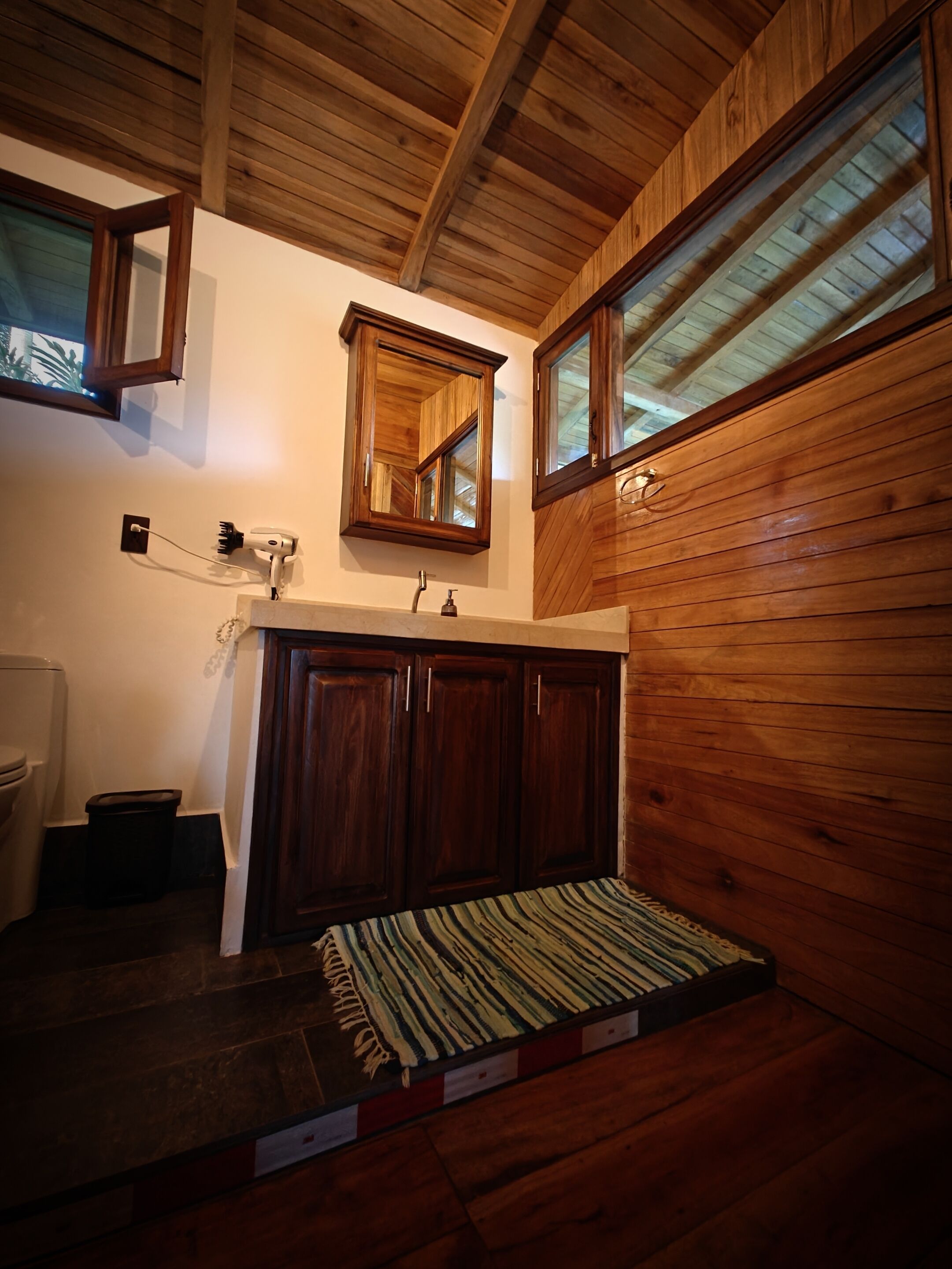 A wooden cabin bathroom with a wooden vanity, a mirror, and a window.