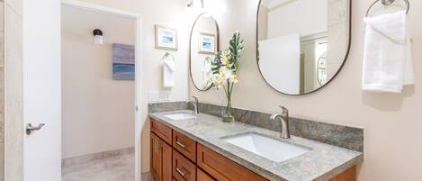 A bathroom with two sinks, wooden cabinets, a large mirror, and a toilet paper holder.