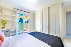 Una camera da letto con un letto, una scrivania con una sedia, una finestra vista e una porta.