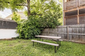Enjoy a serene backyard retreat with a picnic table and benches surrounded by lush greenery.