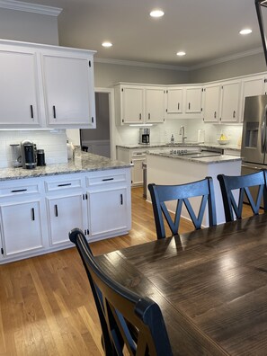 Une cuisine moderne avec des meubles blancs, des plans de travail en granit et un îlot central.