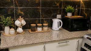A kitchen with a granite countertop, a microwave, a kettle, and various jars and mugs. - Casa Rosa - المهندسين (Giza)