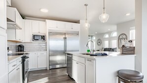 A modern kitchen with white cabinetry, stainless steel appliances, and a wooden floor. - King bed, water and city view, gourmet kitchen, Jewel of Fairhaven  FT505 (Bellingham)
