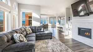 A modern living room with a sectional sofa, a fireplace, and a large TV. - King bed, water and city view, gourmet kitchen, Jewel of Fairhaven  FT505 (Bellingham)