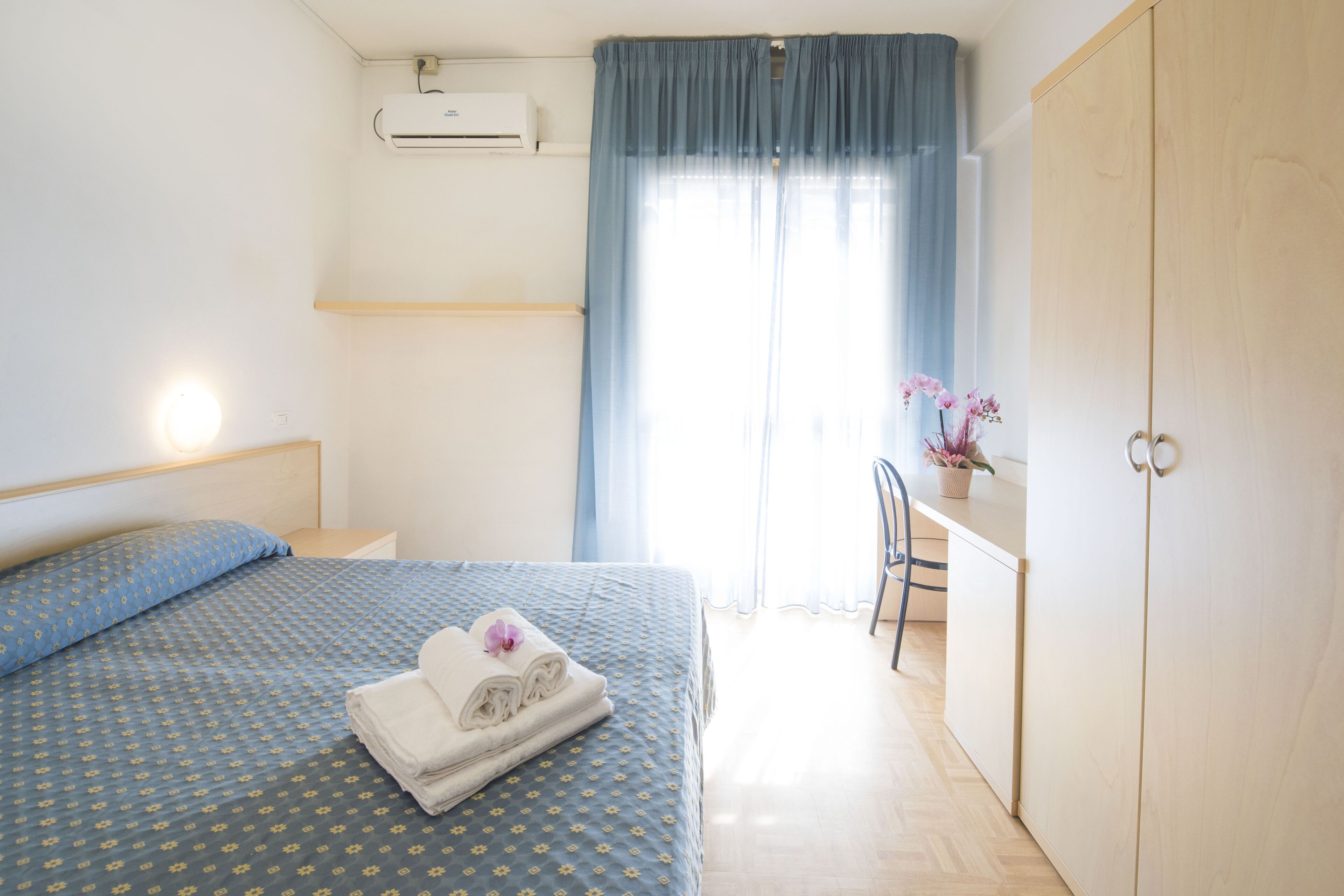 Una habitación de hotel con cama, escritorio, silla y armario.