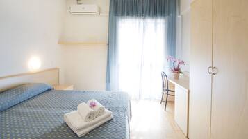 Una habitación de hotel con cama, escritorio, silla y armario.
