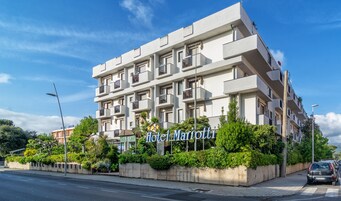 Un hotel de varios pisos con balcones y un letrero que dice "Hotel Mariotto".