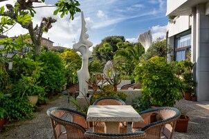 Un patio al aire libre con mobiliario de mimbre, una mesa de piedra y plantas en macetas.