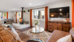 Een woonkamer met een pooltafel, een open haard, een televisie en een bank.