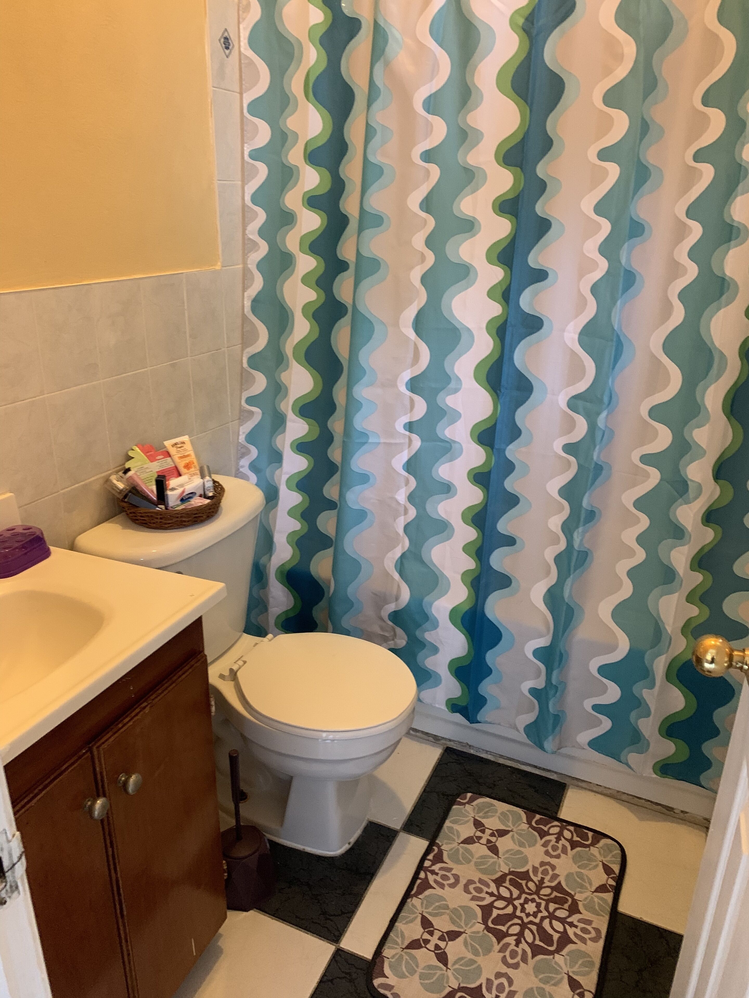 A bathroom with a toilet, a sink, and a shower curtain with a wavy pattern.