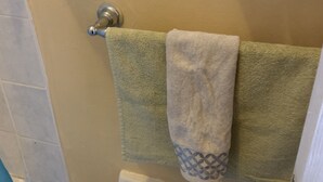 A bathroom with a toilet paper holder, two towels, and a shower curtain. - Studio Apartment in Negril - 2 minutes walk from the Community Beach! (Negril)