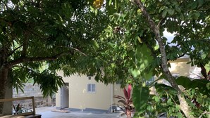 A courtyard with a wooden bench, a concrete pathway, and a building with a window and a door. - Studio Apartment in Negril - 2 minutes walk from the Community Beach! (Negril)