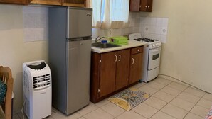 A compact kitchen with a refrigerator, stove, and sink. - Studio Apartment in Negril - 2 minutes walk from the Community Beach! (Negril)