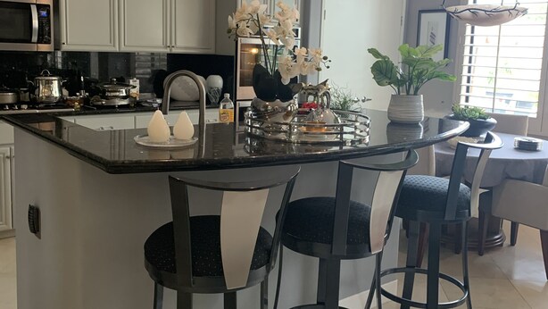 A modern kitchen with a central island, bar stools, and pendant lighting.