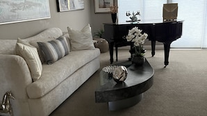 A living room with a sofa, a piano, and artwork on the walls.