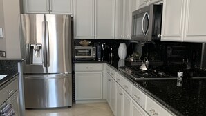 A modern kitchen with white cabinetry, stainless steel appliances, and a black countertop.