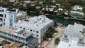 A high-rise building with multiple floors, a river in the background, and a city skyline. - Modern Apartment| City Views + Easy Beach Access (Miami)