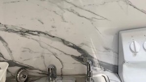 A kitchen with a marble countertop, a sink, and a stove. - Modern Apartment| City Views + Easy Beach Access (Miami)