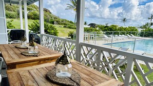 Ein Holztisch mit Glasbehältern und einer Laterne, mit Blick auf einen Pool und üppiges Grün.