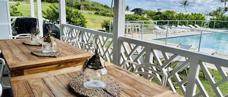 A wooden table with glass jars and a lantern, overlooking a pool and lush greenery.