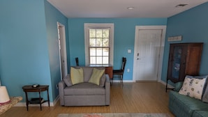 A living room with a grey sofa, a green armchair, a wooden cabinet, and a patterned rug. - Lovely Guest Cottage min from Perdido Key Beaches (Pensacola)
