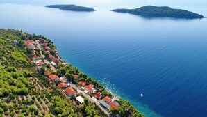 An aerial view of a coastal village with houses along the shoreline, clear blue sea, and small islands in the distance. - Seaside Apartments Markota - Studio Apartment with Sea View (Prižba)