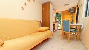 A yellow sofa with a patterned cover, a wooden chair with a cushion, and a small table with a vase. - Seaside Apartments Markota - Studio Apartment with Sea View (Prižba)