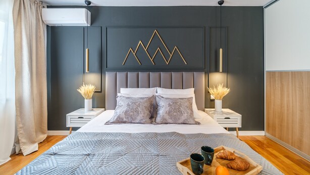 Une chambre moderne avec un grand lit, deux tables de chevet, un panneau décoratif mural et un plateau contenant des éléments pour le petit-déjeuner.