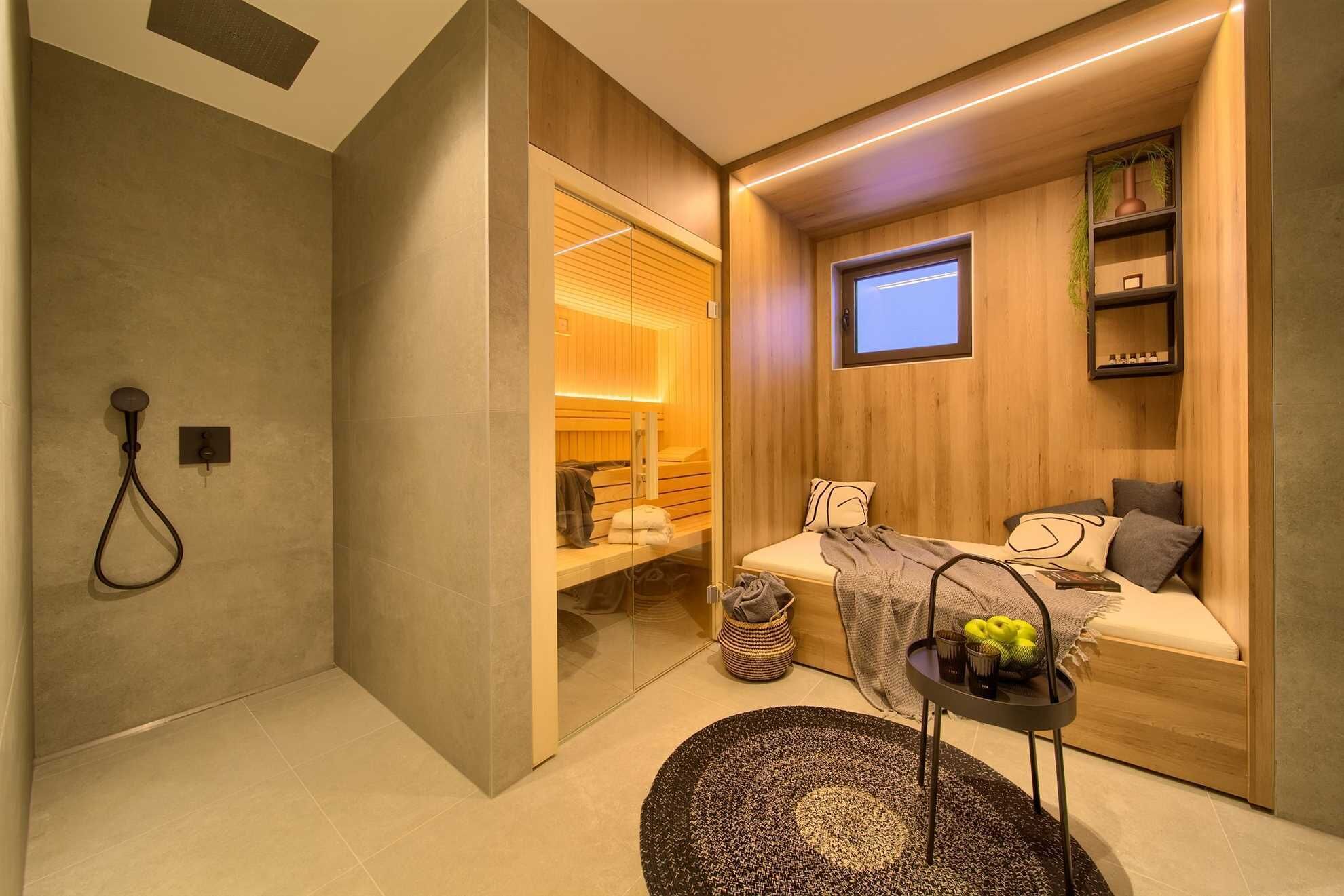 A modern bathroom with a shower, a glass-enclosed sauna, and a seating area with a TV.