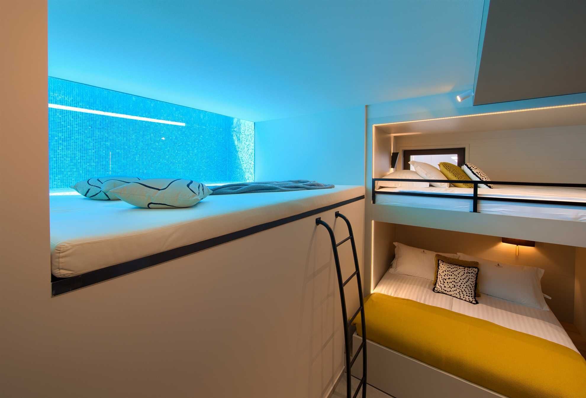 A bunk bed room with a window, a desk, and a ladder.