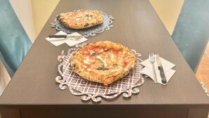 A dining table with two pizzas, a knife, and a fork on a placemat. - 90 m2 apartment in the heart of Rome, 10 meters from the Pantheon (Roma)