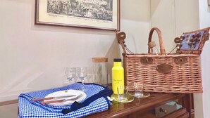 A dining table with a checkered tablecloth, a wicker basket, wine glasses, a bottle of juice, and a framed picture on the wall. - 90 m2 apartment in the heart of Rome, 10 meters from the Pantheon (Roma)
