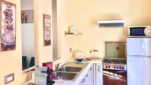 A compact kitchen with a stove, microwave, and refrigerator. There are two sinks, a coffee machine, and a small shelf with kitchen items. - 90 m2 apartment in the heart of Rome, 10 meters from the Pantheon (Roma)