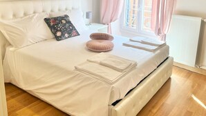 A neatly made bed with white linens, a floral pillow, and pink cushions. - 90 m2 apartment in the heart of Rome, 10 meters from the Pantheon (Roma)