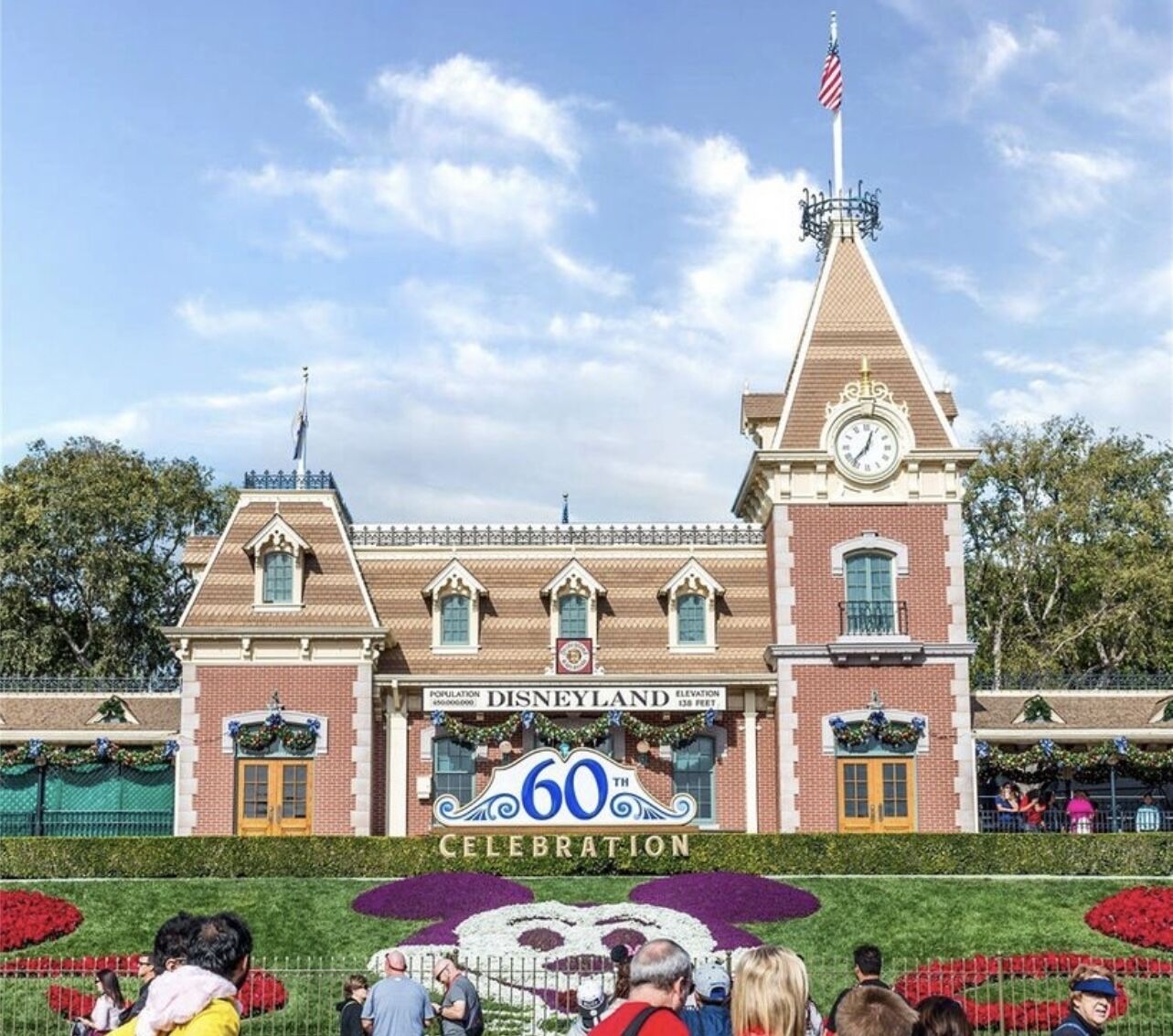 Ein Gebäude mit einem Glockenturm, einem Schild mit der Aufschrift "Disneyland 60th Celebration" und einer Flagge auf dem Dach.