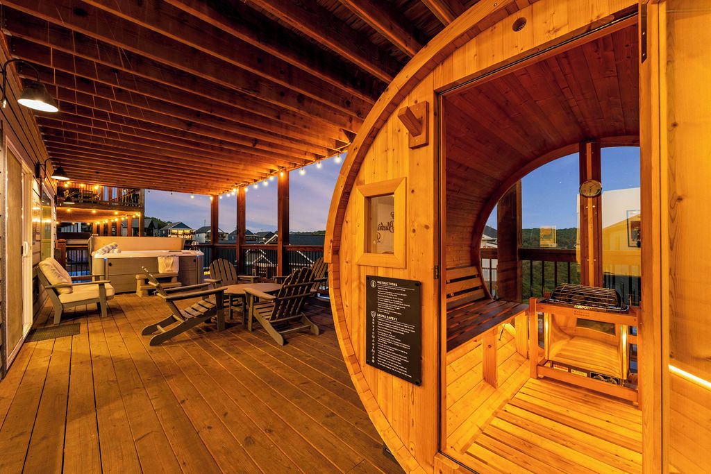 A wooden cabin with a deck, outdoor seating, and a grill.