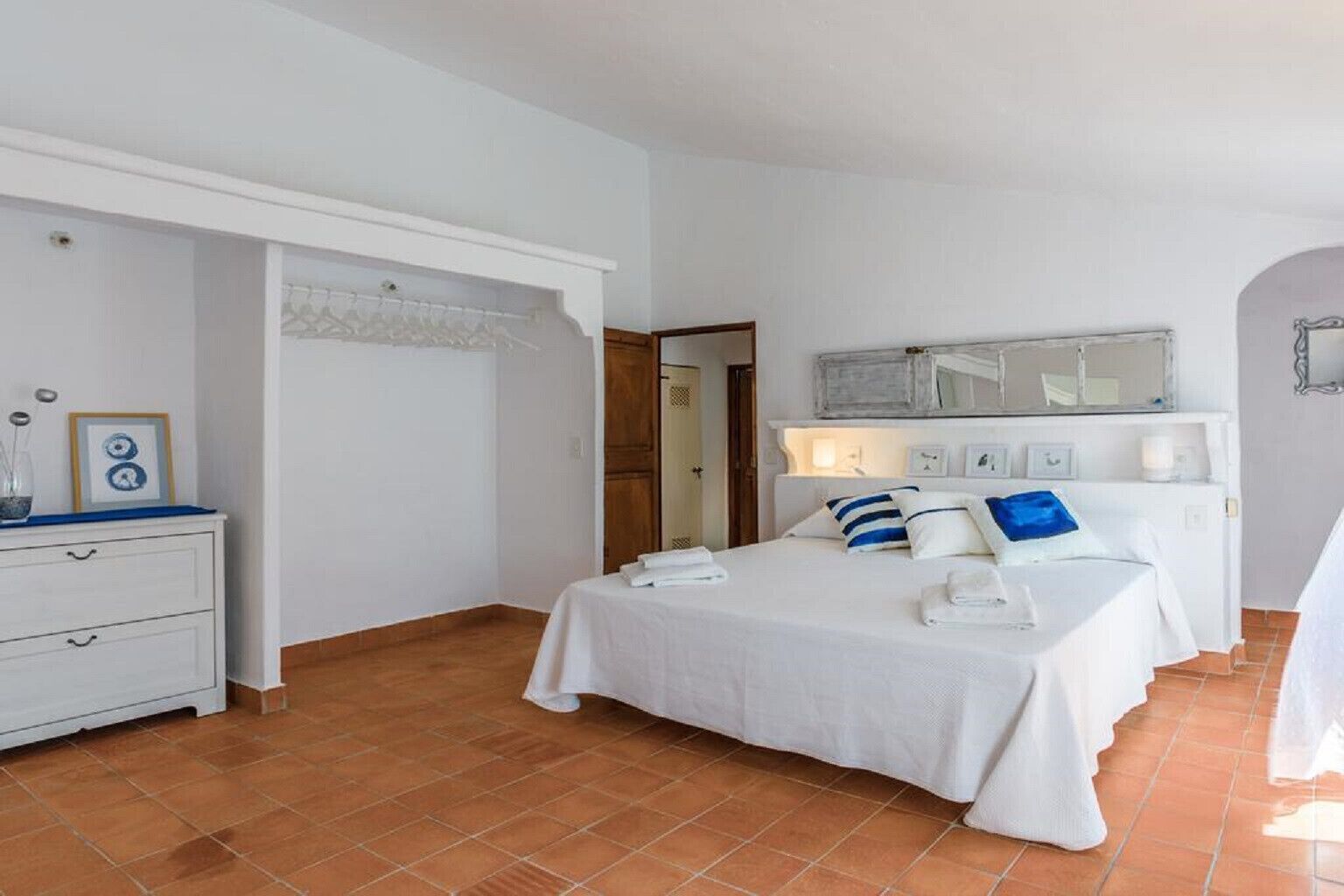 Une chambre à coucher avec un lit, des tables de chevet, une commode et un miroir.