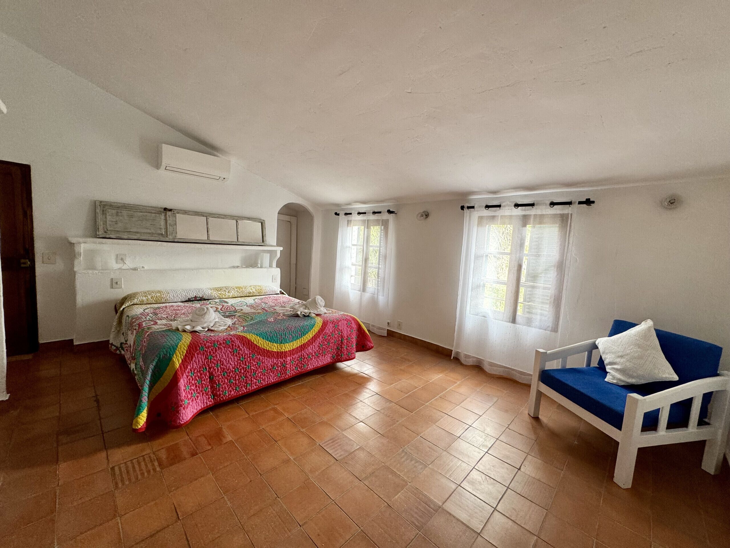 A bedroom with a bed, a chair, and a window.