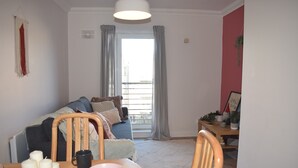 A cozy living room with a sofa, a dining table with candles, and a view of the outside through a window. - Cozy Dublin City Apt near Guinness Storehouse and Temple Bar (Dublin)