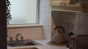 A kitchen with a sink, stove, and toaster. There is a window with blinds, and cabinets with drawers. - Cozy Dublin City Apt near Guinness Storehouse and Temple Bar (Dublin)