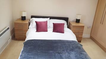 A bedroom with a bed, two nightstands, a dresser, and a wardrobe.