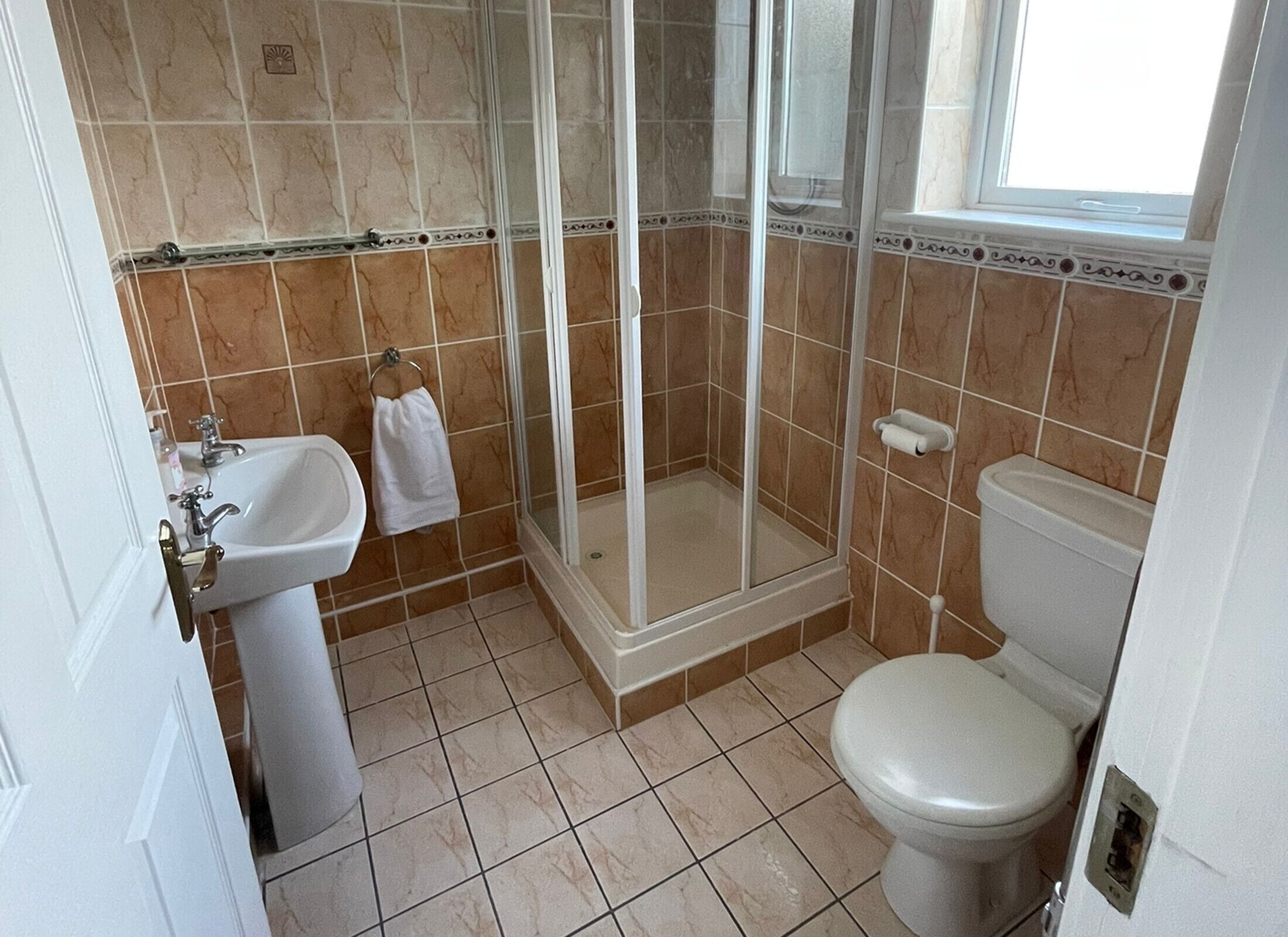 Un bagno con doccia, WC, lavandino e porta asciugamani.