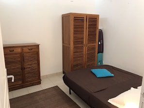 Une chambre avec un lit, une armoire et une valise.