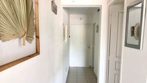 A narrow hallway with white walls, a tiled floor, and a door at the end. - Anse à l'âne apartment  (Les Trois-Îlets)